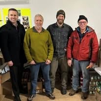 A group of Rotarians unload the pallets and set up the food for packing. L to R: David Spencer, Michael Stamhuis, James Mayne and Roger Perry.